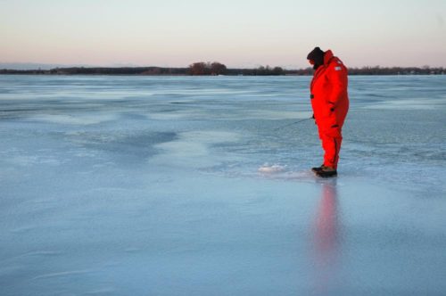 Someone ice fishing in a floatsuit